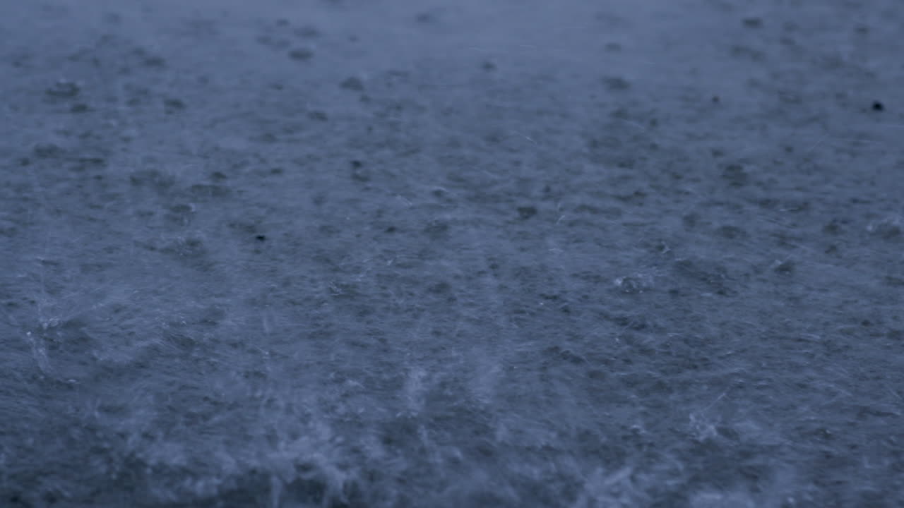 cámara lenta de gotas de lluvia salpicando en un charco durante una tormenta tropical que causa inundaciones