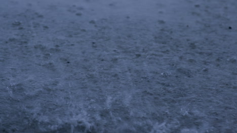 slow mo of rain droplets splashing in a puddle during a tropical storm causing flooding