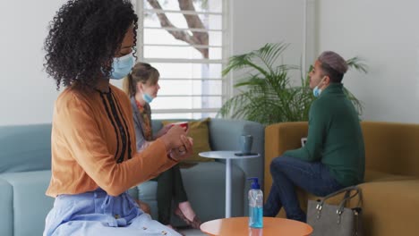 woman wearing face mask sanitizing her hands at office