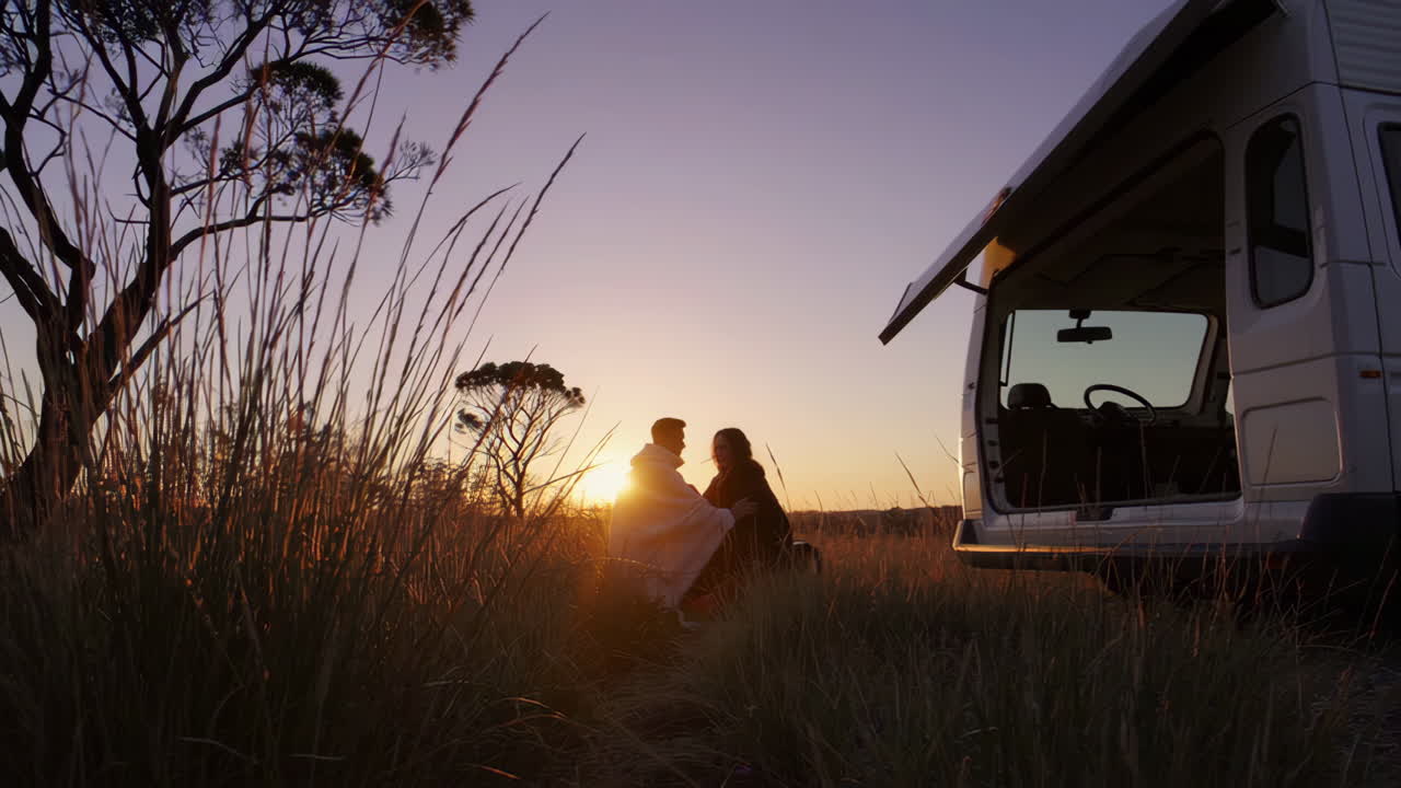 Couple enjoying a romantic sunset by their campervan