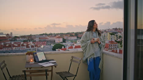 relaxed businesswoman holding cappuccino standing city view balcony at evening