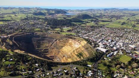 gold mining pit in the middle of waihi town, aerial reveal of new zealand cityscape and coastal scenery