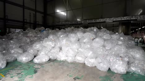 a large quantity of used plastic boxes, wrapped in plastic bags, is stored in a spacious warehouse.