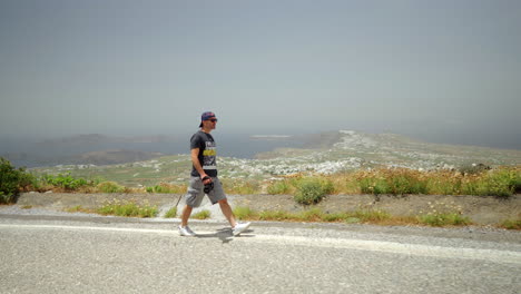 one man holding a camera walks on a high point of santorini island in greece