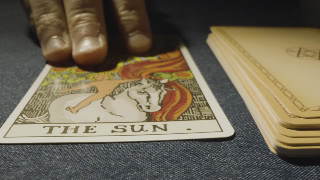 disparo de cerca de una persona que da la lectura de la tarjeta del tarot colocando la tarjeta del sol en la mesa