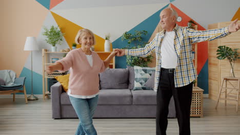 happy elderly couple dancing at home