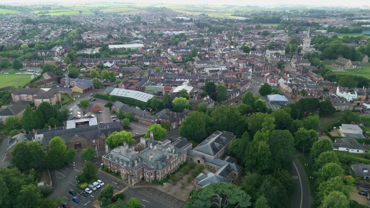 Aerial drone orbit panning view of small English town with historic residential buildings and traditional architecture in rural countryside UK Europe