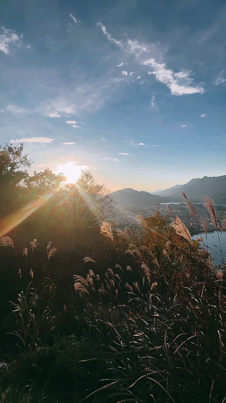 Atardecer sobre un paisaje urbano montañoso con lago y llanuras cubiertas de hierba