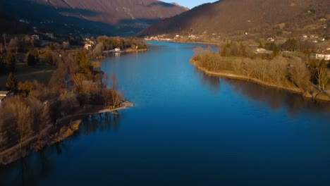 aerial dolly over calm lake endine waters in province of bergamo with pan up reveal of valley