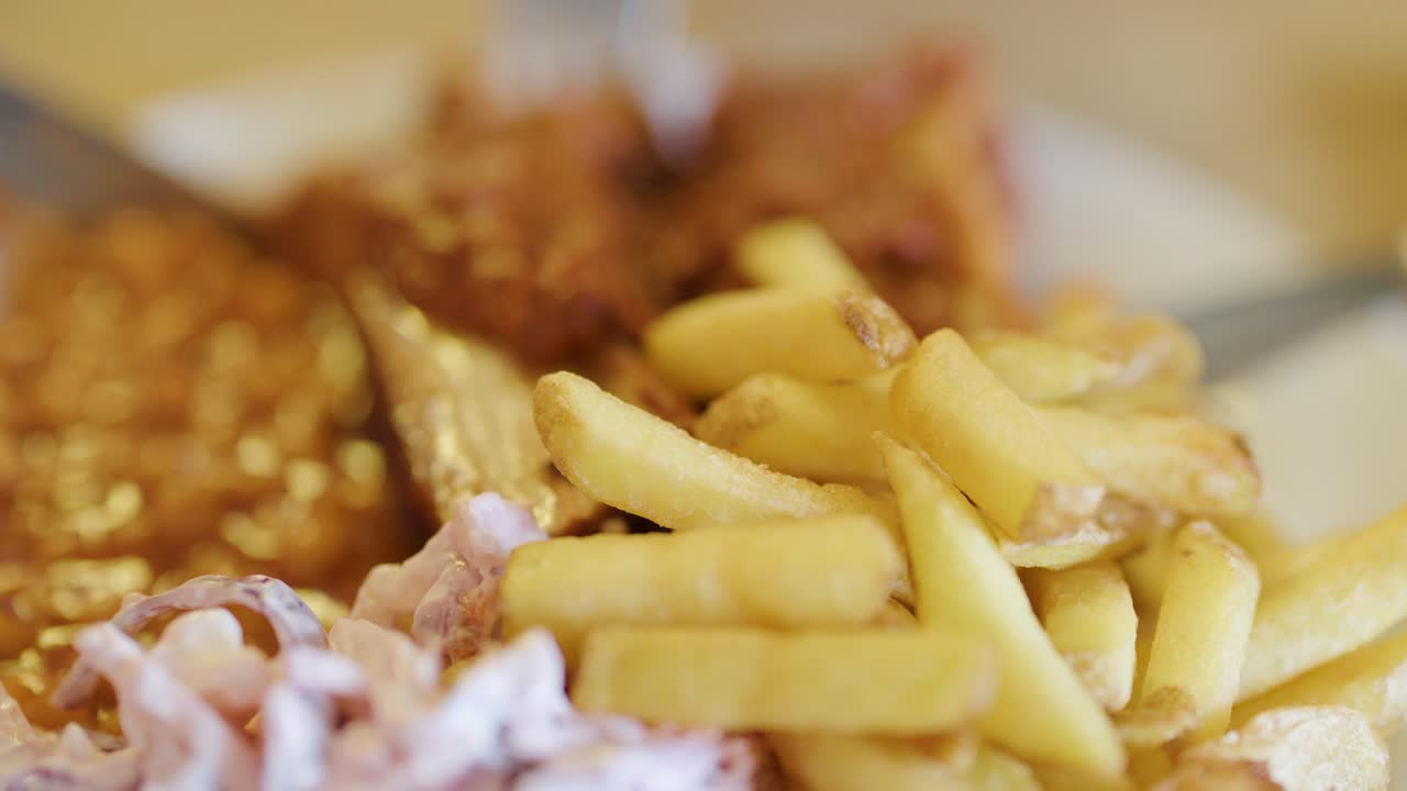 Golden French fries, battered fish fillet, and creamy coleslaw on a plate, captured in a macro close-up with shallow depth of field and warm lighting