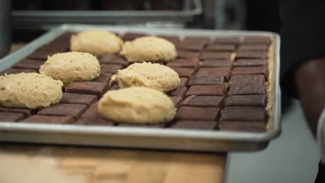 placing chunks of peanut butter dough on to chocolate brownies.