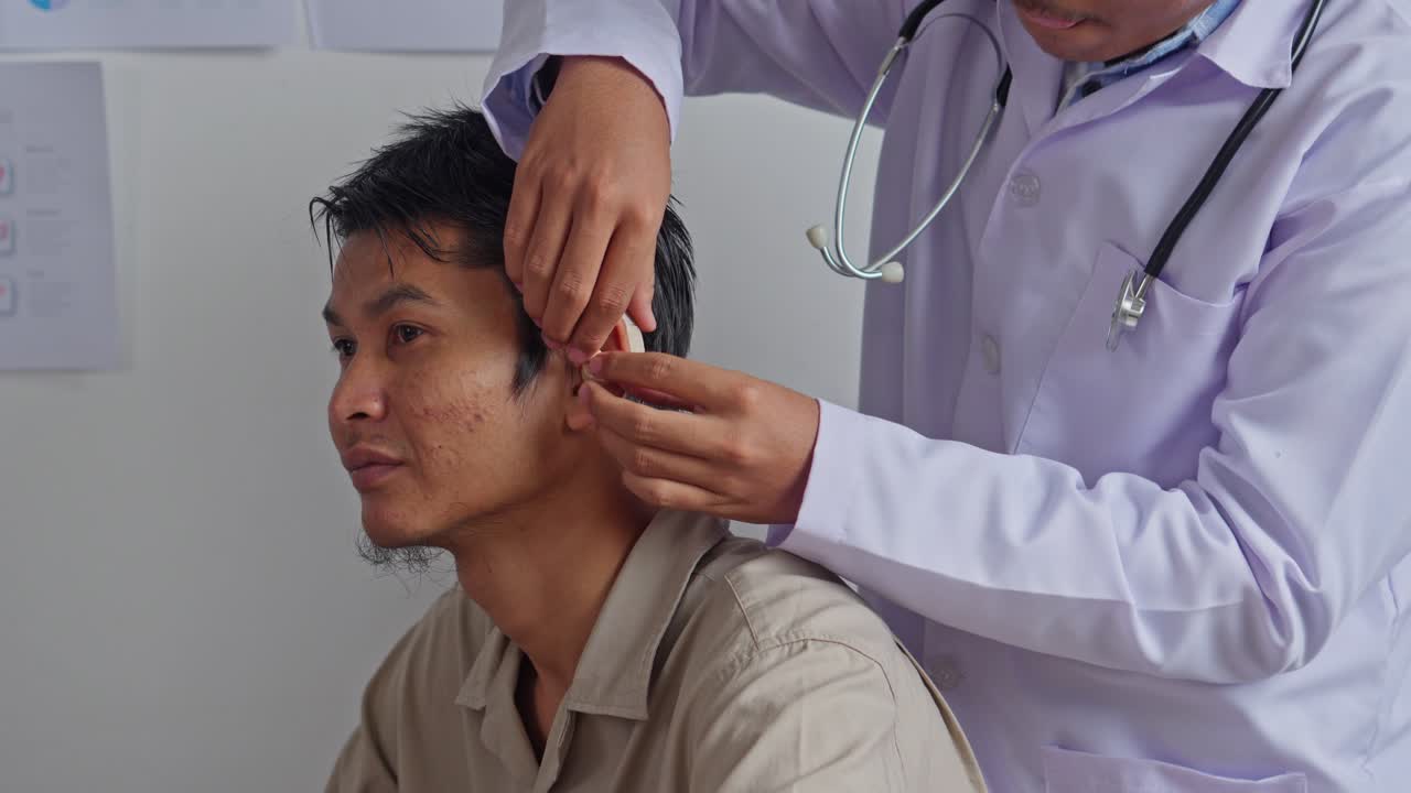 Audiologiste professionnel ajustant un appareil auditif sur un jeune homme en milieu clinique