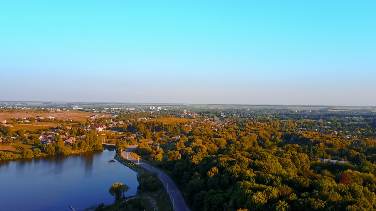 Breath-taking cityscape full of greenery on bright sunny day. River flowing along the provincial city from top view.