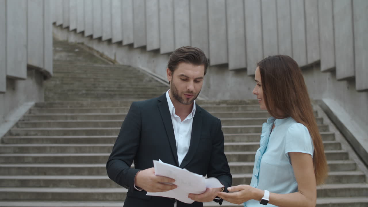 Coppia d'affari che discute all'aperto. Uomo d'affari che lancia documenti in aria.