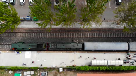 antena: tren detenido en una estación con pasajeros caminando en la plataforma