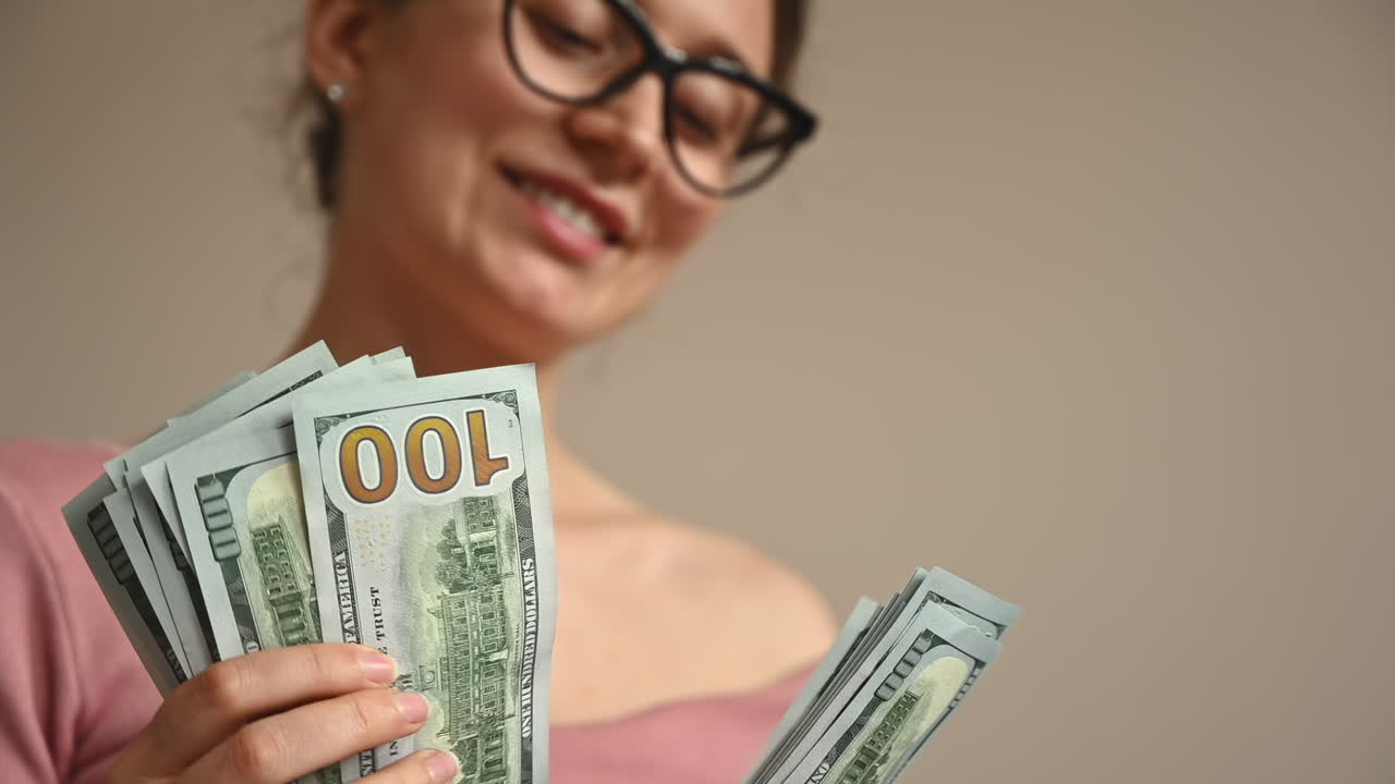 Smiling woman counting multiple one hundred dollar bills in her hands