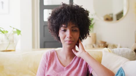 Video-portrait-of-smiling-biracial-woman-relaxing-at-home,-with-copy-space