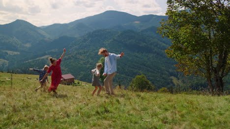 playful family playing running like planes on meadow. parents with kids have fun