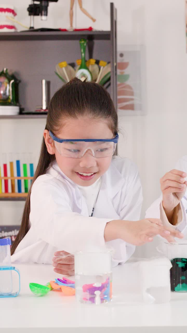 Seorang siswa Asia muda berjas lab melakukan percobaan kimia dengan es kering.