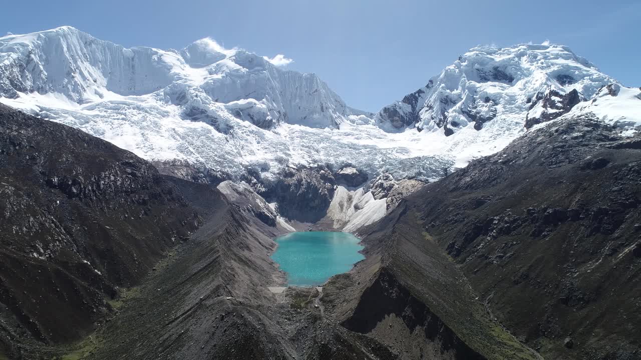 A stunning turquoise glacial lagoon nestled between towering snow-covered mountains. A breathtaking scene for travel blogs, adventure videography, and premium videos
