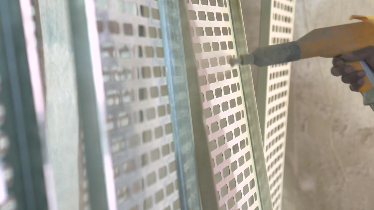 Worker Spray Painting Perforated Metal Panels In A Metalworking Production Factory, Close Up Shot.
