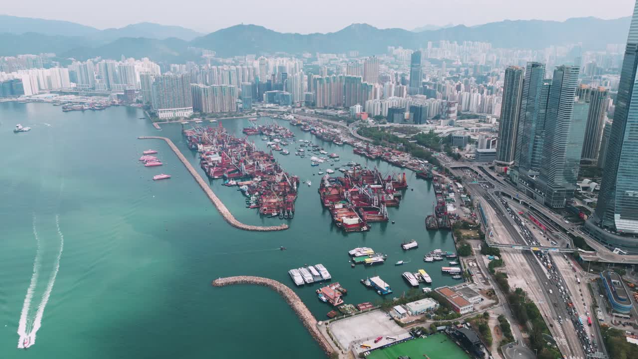 Panoramisk luftfoto af Hongkongs havn på en solrig dag, med fragtskibe, containerterminaler og den omkringliggende bysilhuet