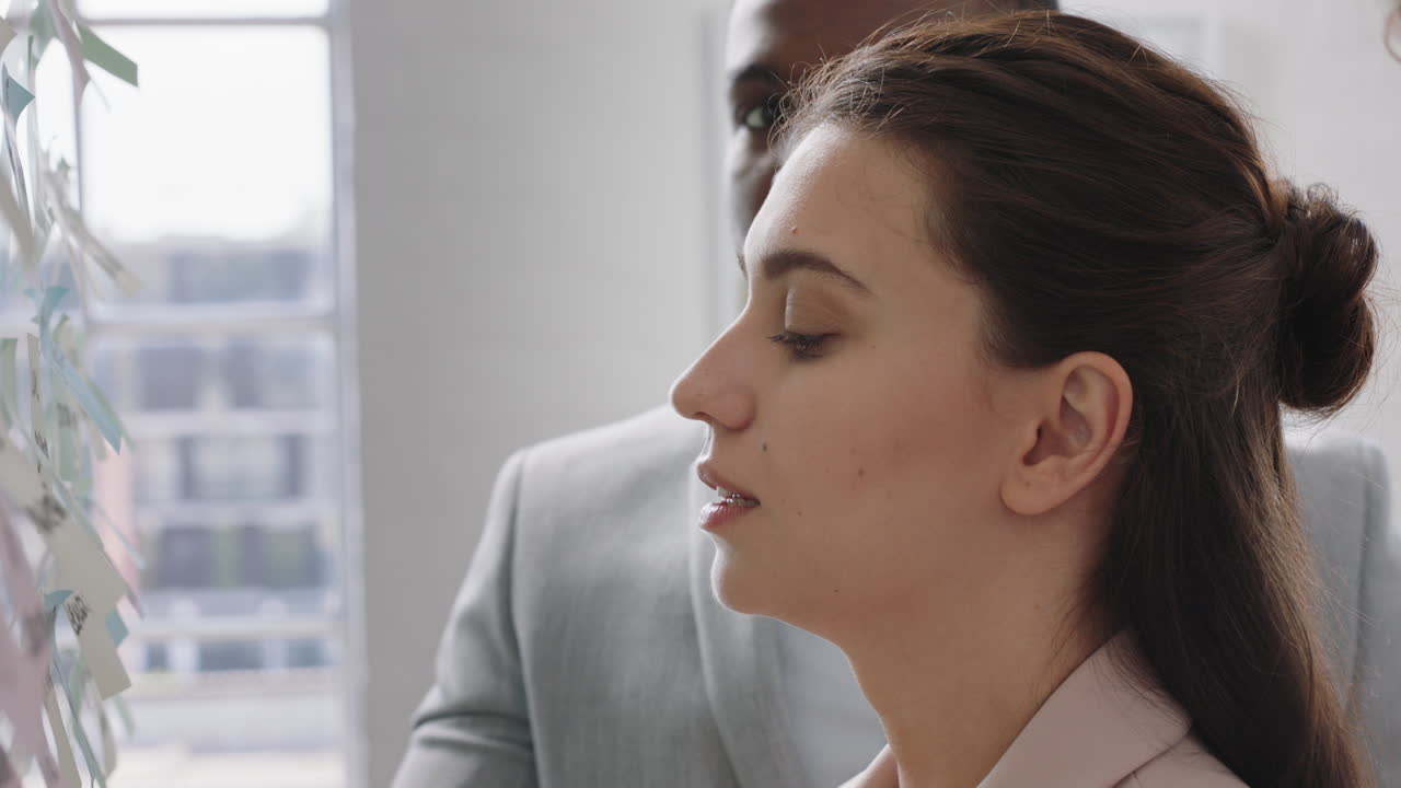 giovane donna d'affari che usa note adesive, fa brainstorming, risolve problemi con diversi colleghi, condivide idee creative per la soluzione in una riunione d'ufficio