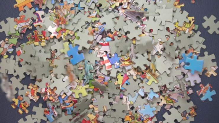 Molti pezzi di puzzle che cadono su una superficie blu scuro - angolazione dall'alto, rallentatore