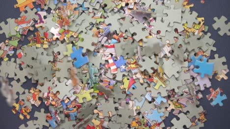 Many Puzzle Pieces Falling Down On Dark Blue Surface - high angle, slow motion