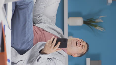 vertical video of home office worker old man getting bad news on the phone.