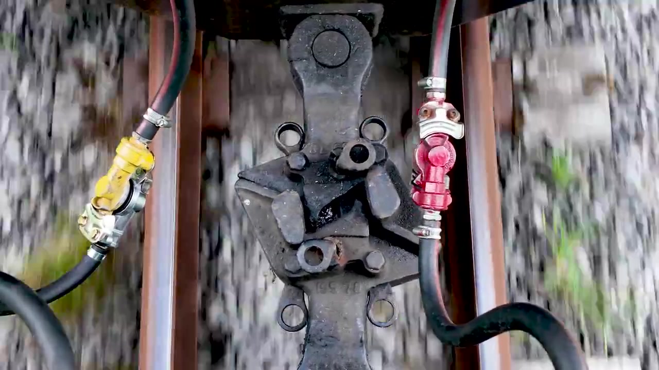 Vista dall'alto di due vagoni ferroviari uniti da accoppiatori che viaggiano velocemente sul binario.