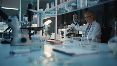 surprized female reseach scientist makes an important discovery while researching virus vaccine samples under the microscope. she calls colleagues and shares her success with fellow bioengineers.