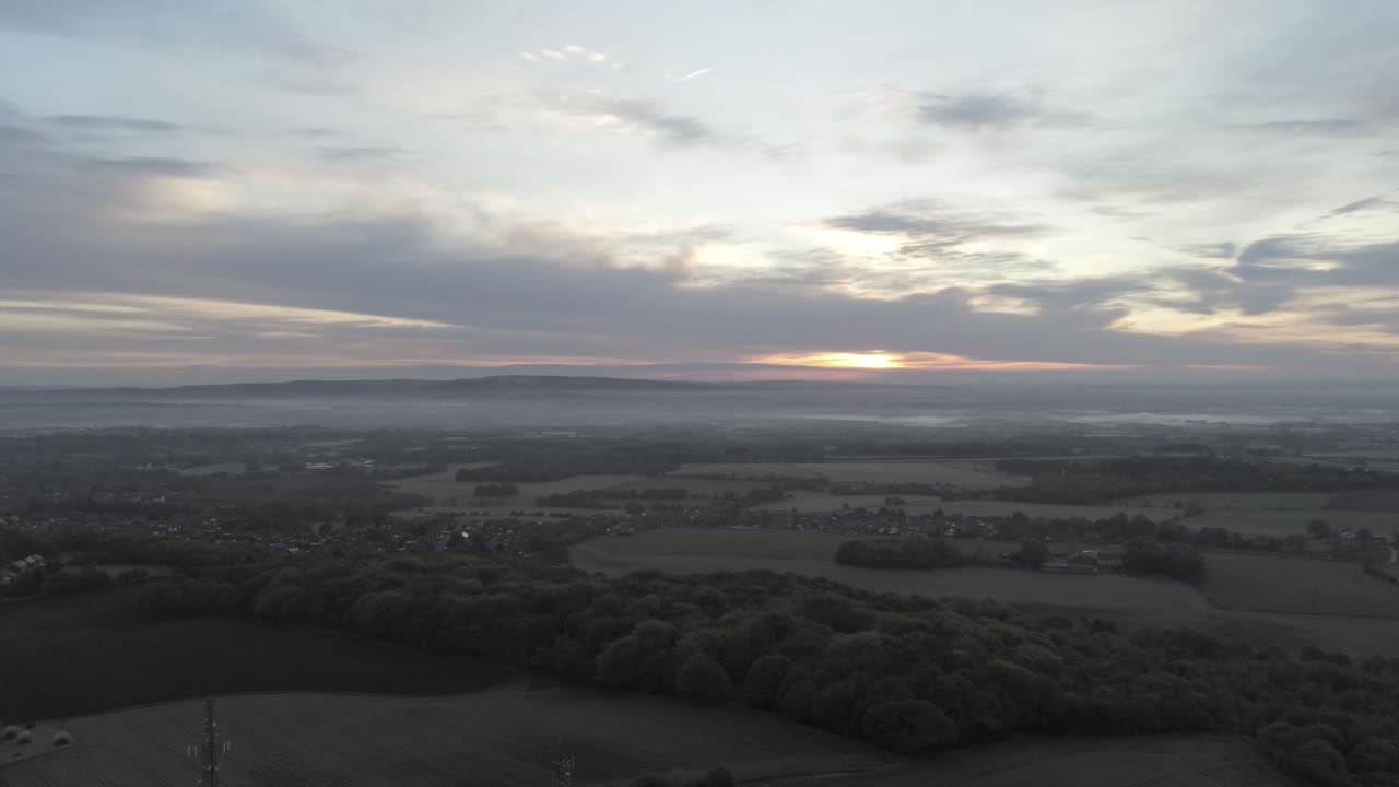 Early sunrise aerial telecom towers on agricultural rural farmland countryside slow drift left