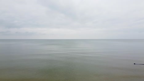 Aerial view of Baltic sea coast in overcast spring day, steep seashore dunes damaged by waves, coastal erosion, climate changes, low angle revealing drone shot moving forward