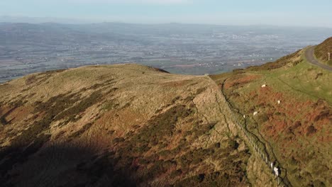 Early-sunlight-on-highland-hiking-mountain-peak-aerial-view-across-vast-frosty-idyllic-farmland-countryside-moving-forward