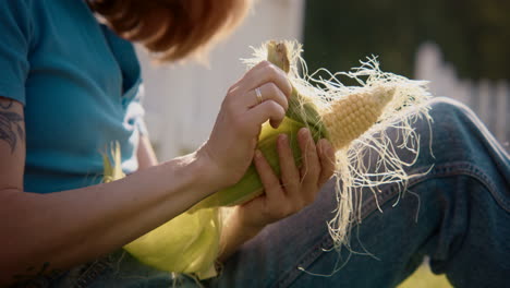 woman husking corn outdoors