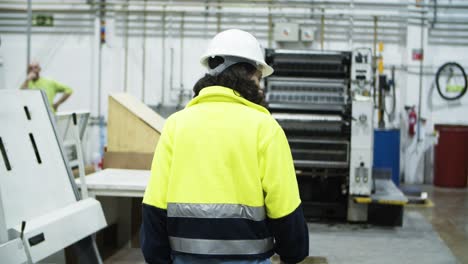 Back-view-of-female-printing-technician-walking-at-factory