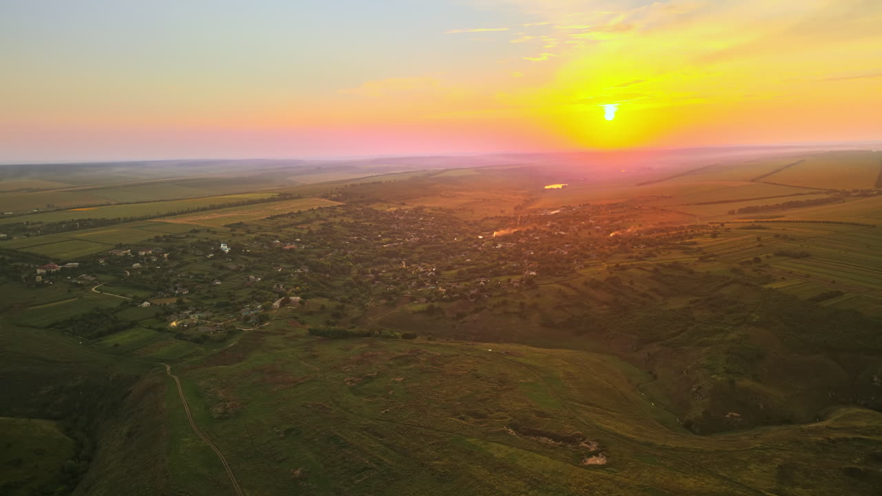 Aerial drone view of nature in Moldova at sunset. Village, sun, fields and hills
