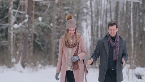 young married couple walks through the winter forest. a man and a woman look at each other laughing and smiling in slow motion.