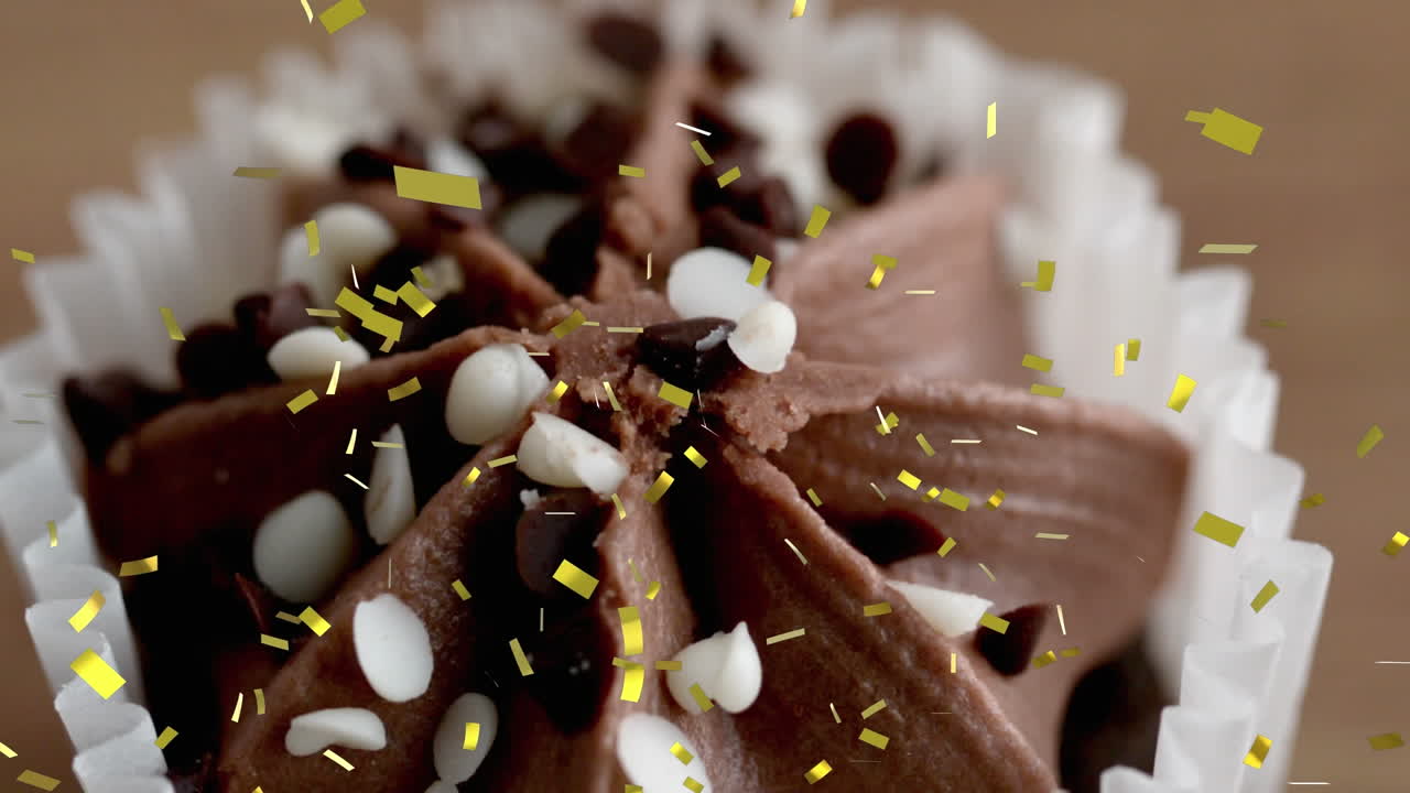 animación de confeti dorado cayendo de cerca de un pastel de chocolate.