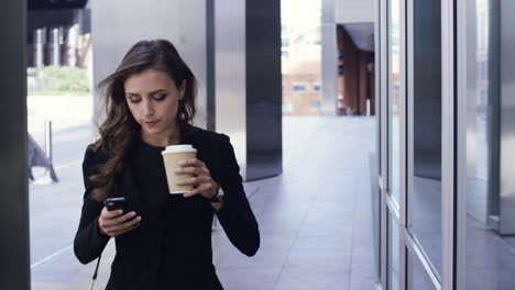 atractiva mujer de negocios viajera que usa un teléfono inteligente caminando en la ciudad de londres