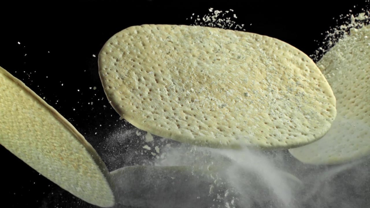 Impasto crudo per pizza e farina che fluttuano su sfondo nero