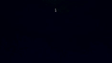 drone shot revealing a fishing boat in the dark vast ocean