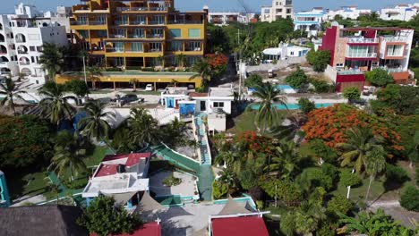 a zoom out shot of a beautiful colorful houses and hotel along side of a wonderful beach at isla mujeres in mexico