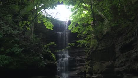 Elegant-forested-mossy-waterfall-that-pours-down-below-a-arched-bridge-in-the-middle-of-Matthiessen-state-park