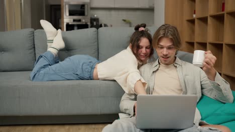 Young-adult-couple-talking-using-laptop-computer-at-home-watching-video