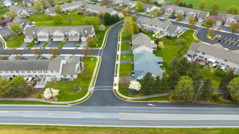 aerial drone time lapse of a suburban neighborhood with neatly aligned townhouses and blossoming spring trees in the usa