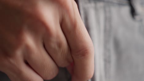 close-up of hand closing zipper of denim jeans.