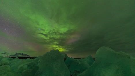 aurora bright green light in the night sky over the ice rock block in the north sea beach in iceland norway nordic country cold climate in winter night sky photography slow-motion time-lapse of stars