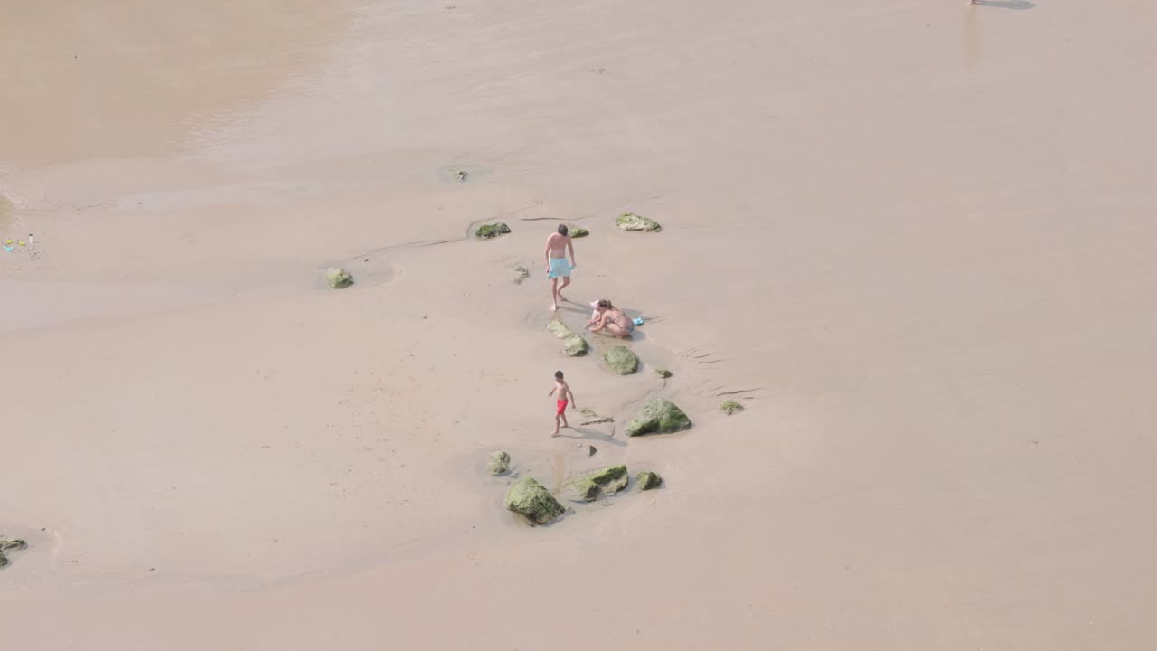 Family playing on some rocks on the shore near the sea